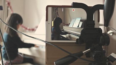 A picture of a cell phone recording a piano student.
