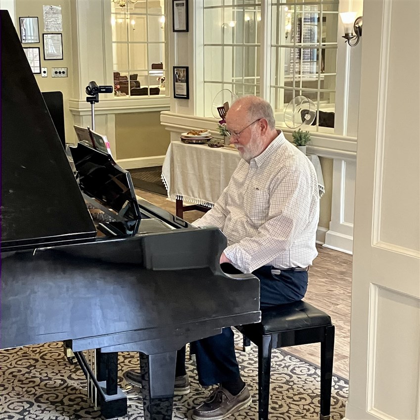 Image of a senior musician passionately performing at a community recital in Fort Worth, sharing their musical talent and experience with the audience.